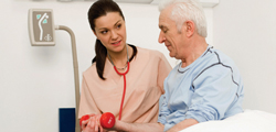 Picture of a female Nurse sitting next to an elderly man on a swing bed.